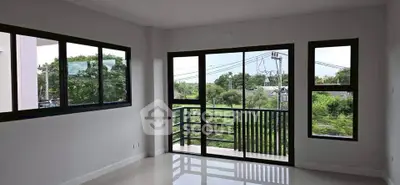 Spacious living room with large windows offering a serene green view, perfect for relaxation.