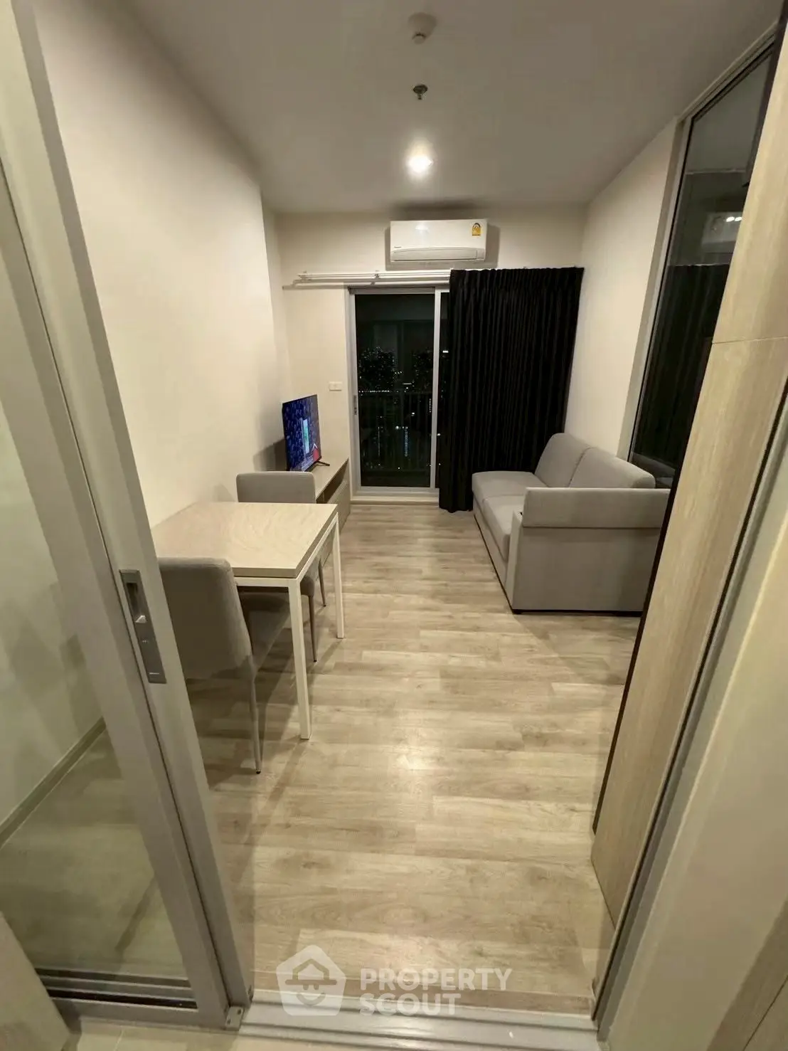 Modern living room with sleek furniture and balcony view in urban apartment.