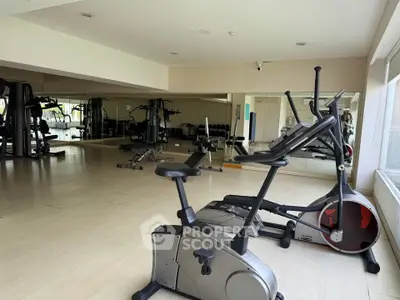 Spacious gym with modern exercise equipment and mirrored walls in a residential building.