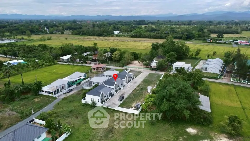 Aerial view of modern residential property surrounded by lush greenery and scenic landscape.