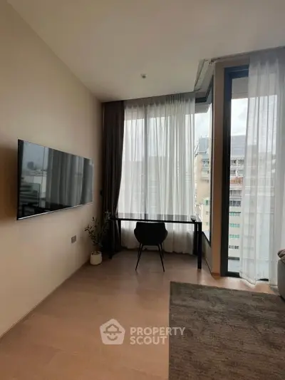 Modern living room with large windows and wall-mounted TV in urban apartment.