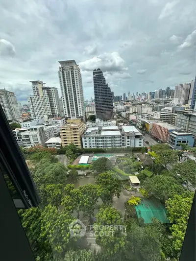 Stunning cityscape view from high-rise building overlooking lush greenery and urban skyline.