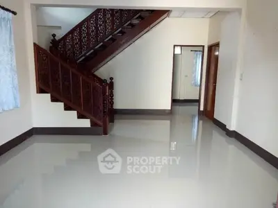 Spacious and bright entryway with elegant wooden staircase and gleaming tiled floors, leading to a well-lit corridor with modern doors.