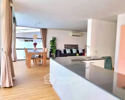 Spacious open-plan living room with modern kitchen and dining area, featuring elegant decor and natural light.