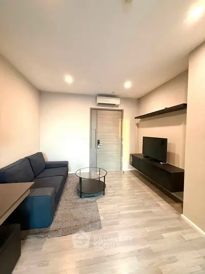 Modern living room with sleek furniture and neutral tones, featuring a cozy sofa and wall-mounted TV.