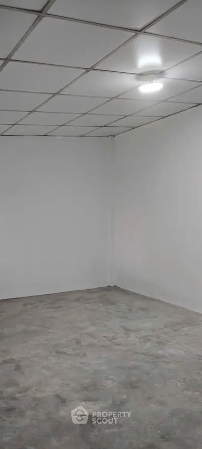 Spacious empty room with tiled ceiling and concrete floor, ideal for customization.