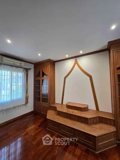 Elegant living room with wooden built-in shelves and polished hardwood floors.