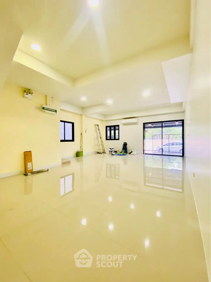Spacious open-plan living room with glossy tiled floors and large windows.