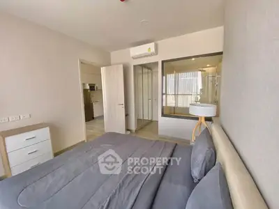 Modern bedroom with sleek design and glass partition, featuring neutral tones and stylish furnishings.