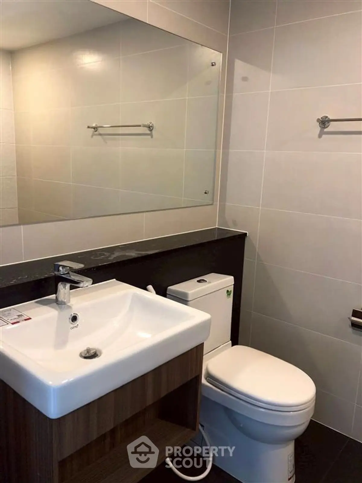 Modern bathroom with sleek fixtures and large mirror in contemporary apartment.