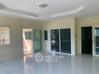 Spacious living room with large windows and tiled flooring