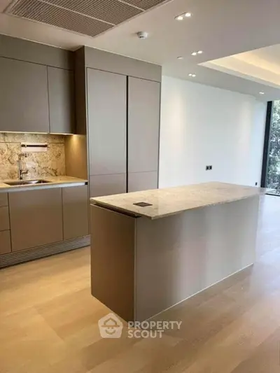 Modern kitchen with sleek cabinetry and marble countertop in luxury apartment.
