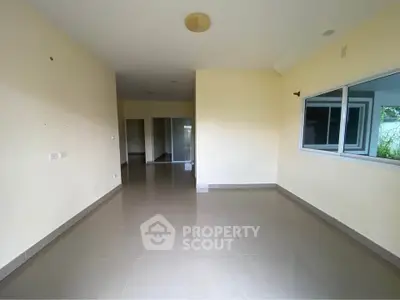 Spacious empty room with large window and neutral tones, perfect for customization.