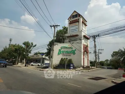 Unique building exterior with prominent signage and lush surroundings, ideal for business visibility.