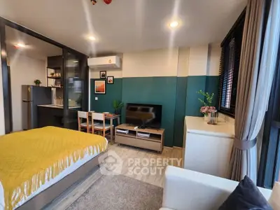 Modern studio apartment with stylish decor and open layout, featuring a cozy bed and sleek kitchen area.