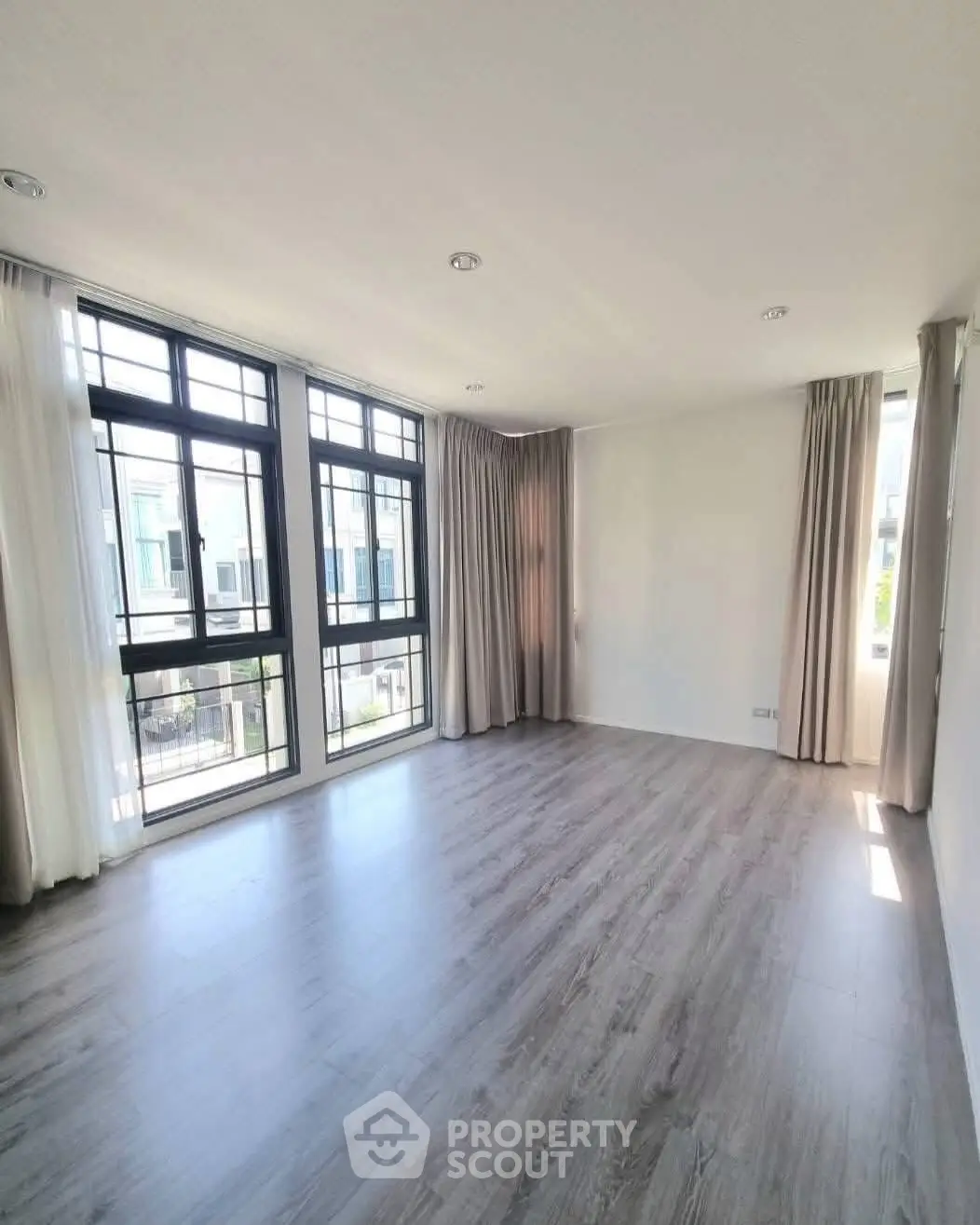 Spacious empty living room with large windows and elegant curtains