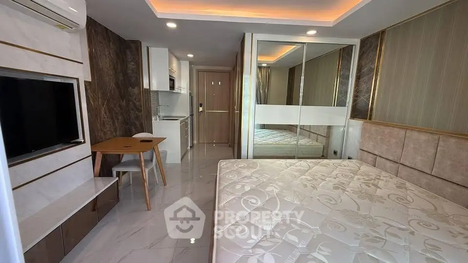 Modern studio apartment with sleek design, mirrored wardrobe, and compact kitchen area.