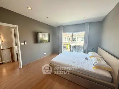 Modern bedroom with large window and wall-mounted TV in stylish home