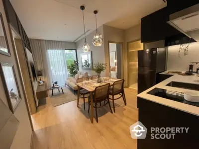 Modern open-plan kitchen with sleek black appliances flows into a cozy dining area, complemented by stylish pendant lighting and warm wooden flooring.