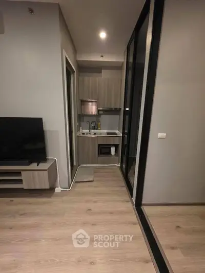Modern compact apartment with sleek kitchen and cozy living area, featuring stylish wood flooring and contemporary design.