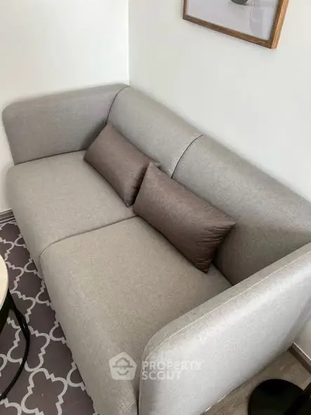 Cozy modern living room with stylish gray sofa and decorative pillows, perfect for relaxation.