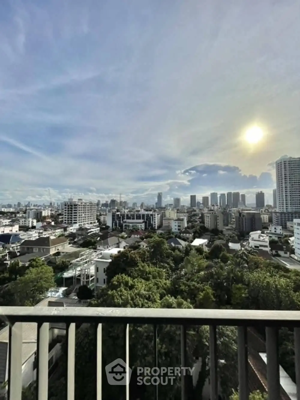 Stunning cityscape view from a high-rise balcony overlooking lush greenery and urban skyline.