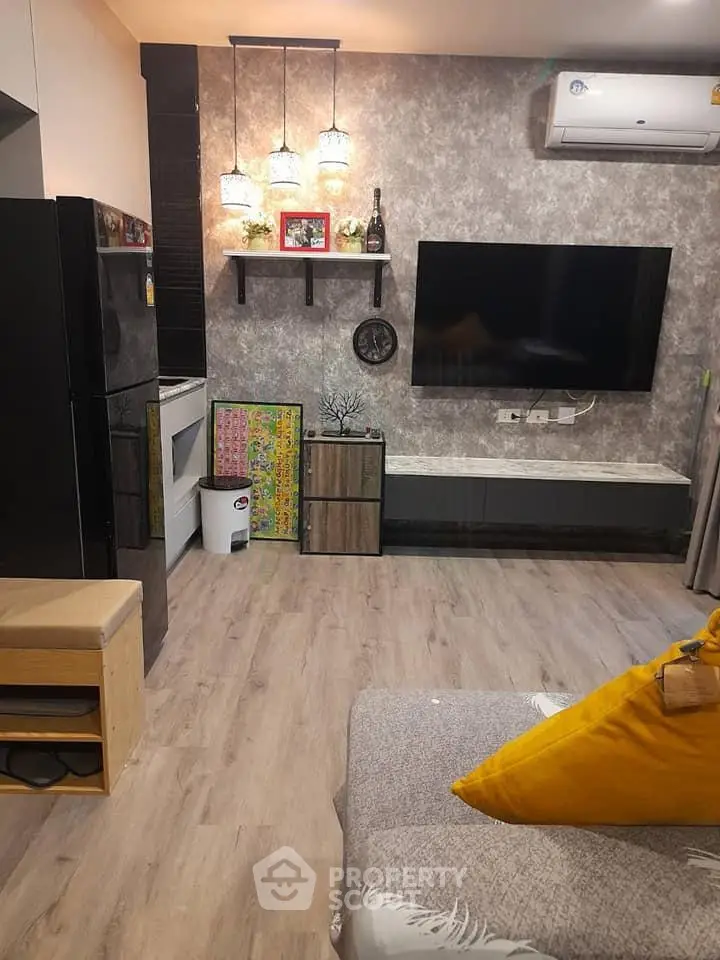 Modern living room with stylish decor and large TV, featuring wood flooring and cozy seating.