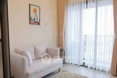 Bright living room with cozy sofa and large window leading to balcony, perfect for relaxation.