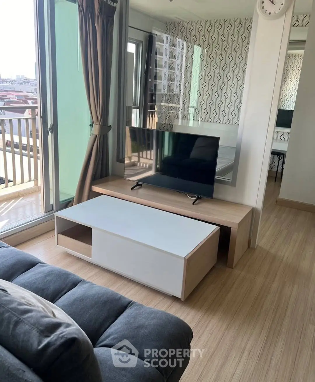 Modern living room with stylish decor and balcony view, featuring a sleek TV setup and cozy seating area.