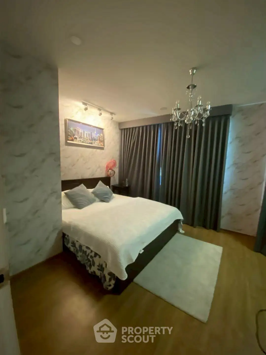 Cozy bedroom with elegant chandelier and modern decor in a stylish apartment.