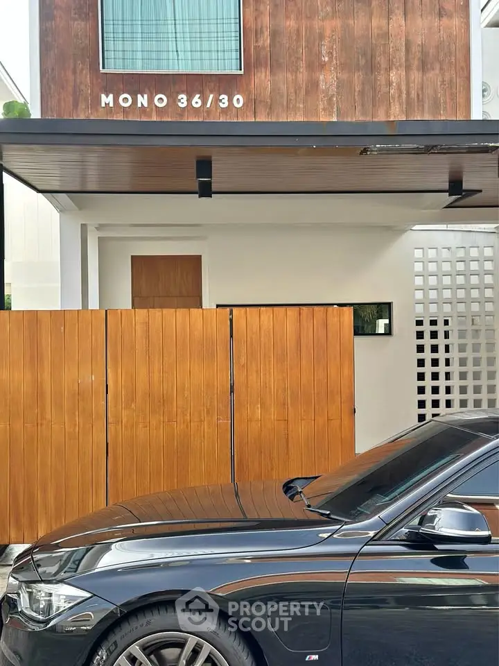 Modern townhouse exterior with wooden accents and sleek car parked in front.