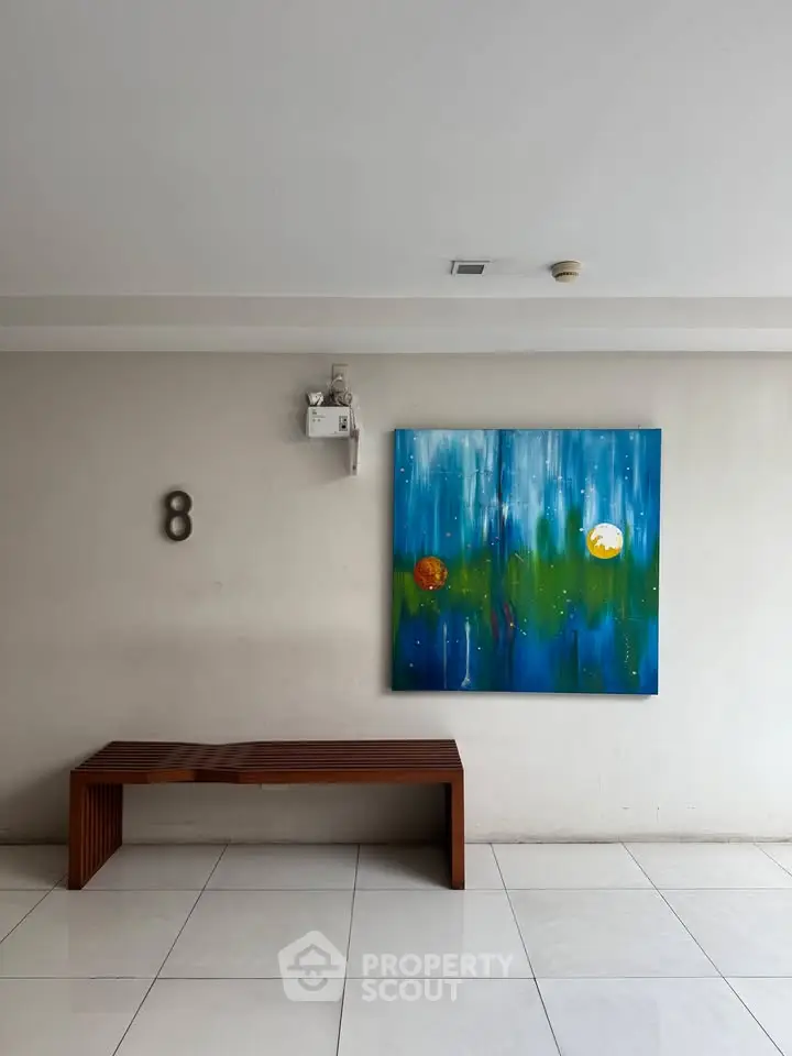Modern building entrance with art and seating, showcasing minimalist design.