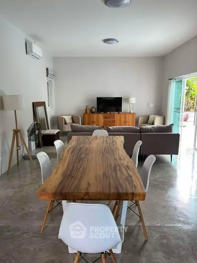 Spacious modern living room with stylish wooden dining table and cozy seating area, perfect for entertaining.