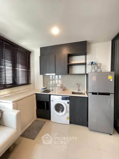 Modern kitchen with sleek cabinetry, washing machine, and fridge in a compact open layout.
