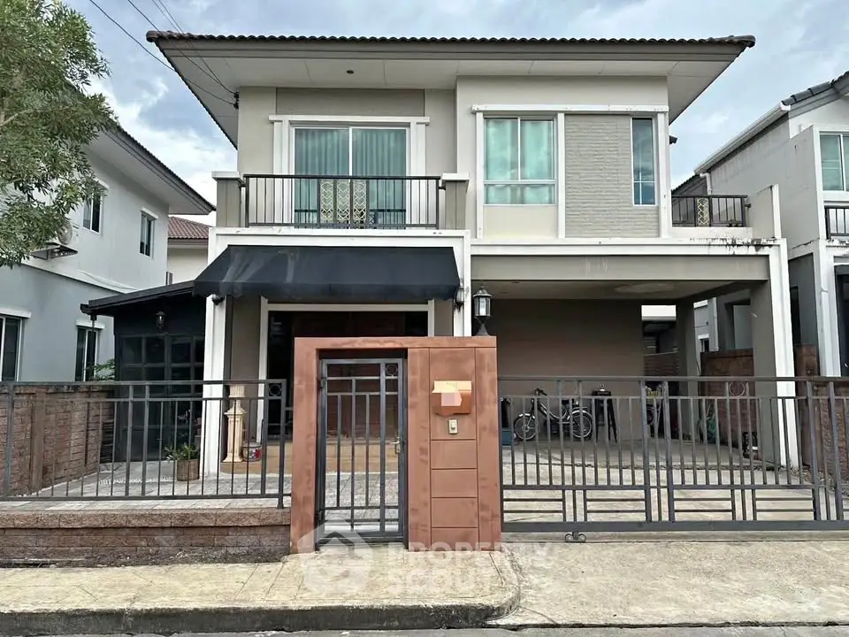 Modern two-story house with gated entrance and balcony in suburban neighborhood.