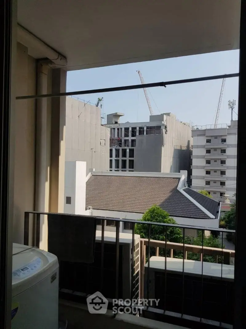 Urban balcony view with construction cranes and modern buildings.