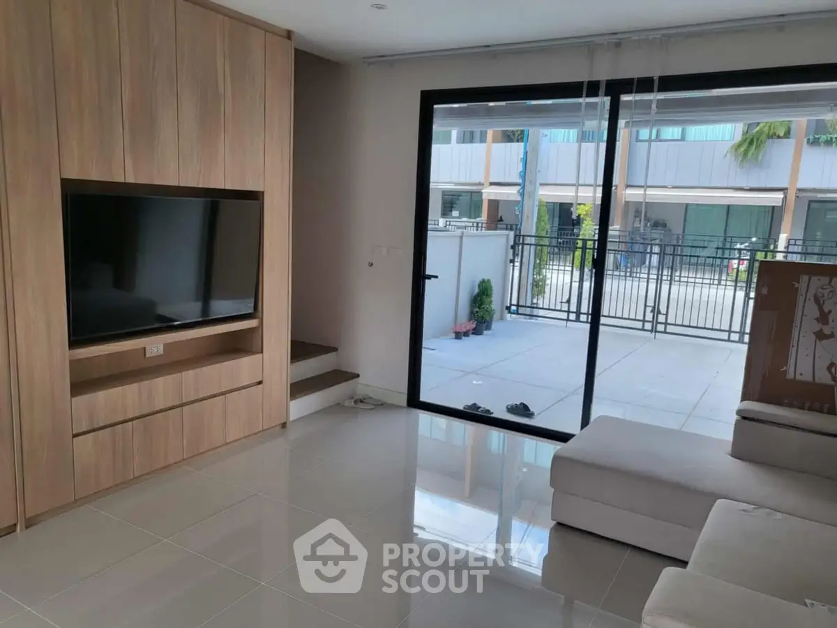 Modern living room with large TV and sliding glass doors to patio