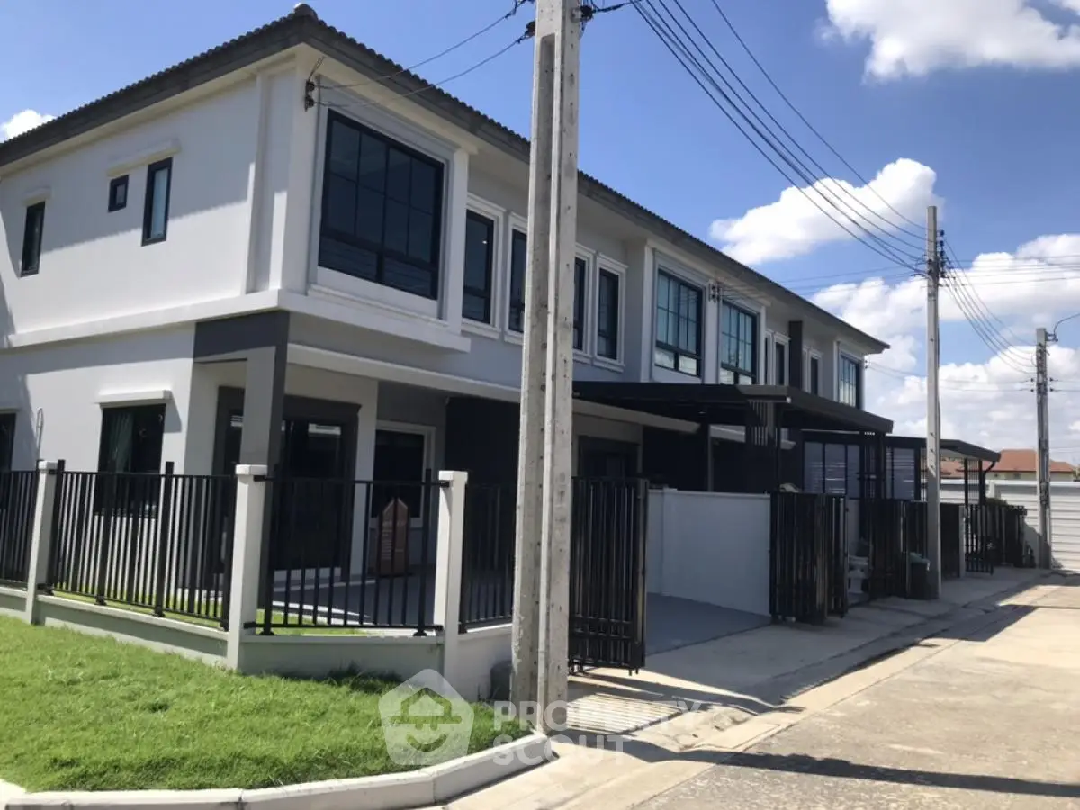 Modern townhouse exterior with sleek design and spacious driveway in a sunny neighborhood.