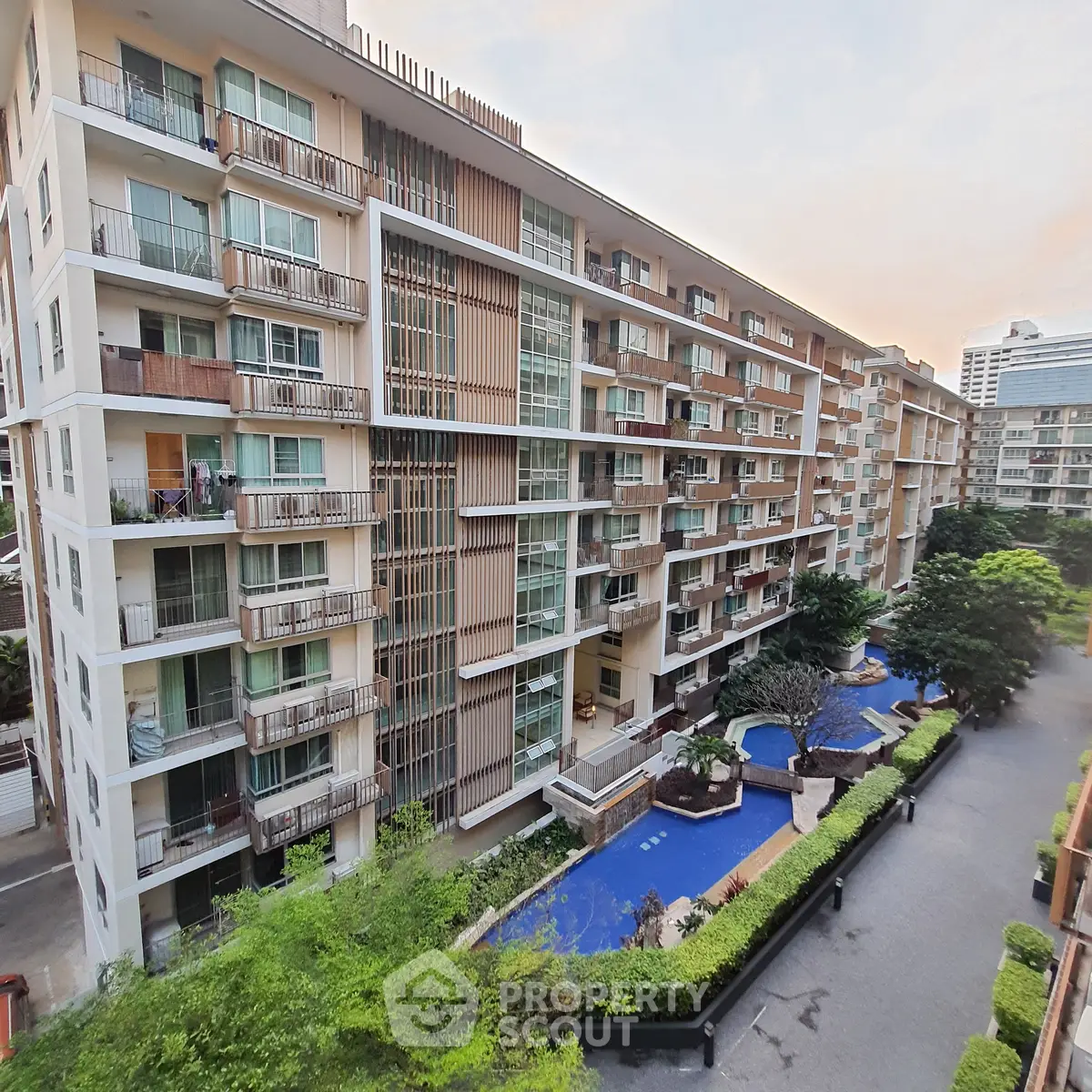 Modern apartment building with lush greenery and pool view, perfect for urban living.