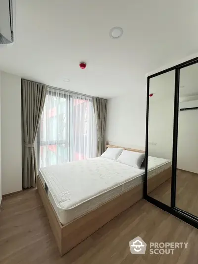 Modern bedroom with large mirror closet and natural light