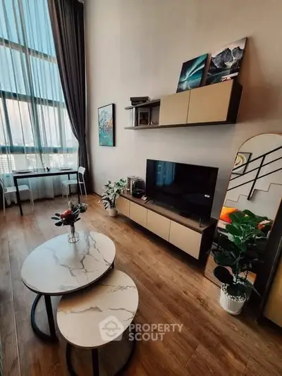 Modern living room with high ceilings, stylish decor, and large windows offering natural light.