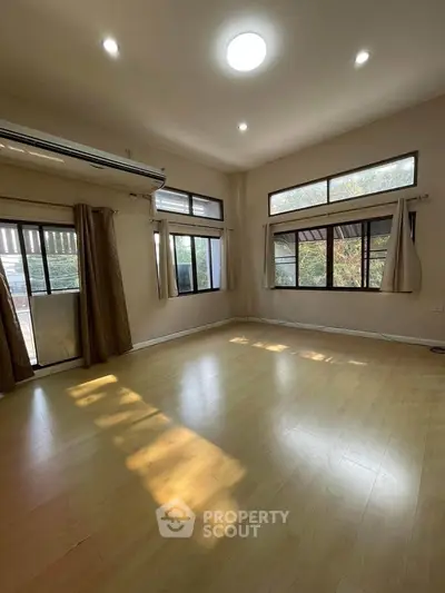 Spacious empty room with large windows and wooden flooring, perfect for customization.
