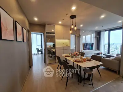 Modern open-plan living and dining area with city view, stylish decor, and elegant lighting.
