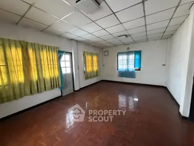 Spacious empty room with wooden flooring and large windows, ideal for customization.