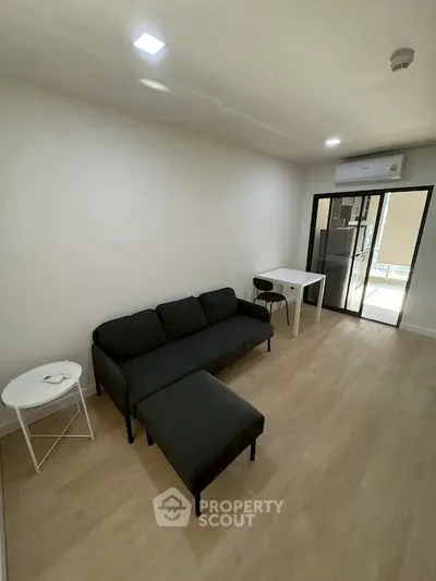 Modern living room with sleek black sofa and minimalist decor in a bright apartment.