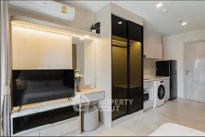Modern studio apartment with sleek design, featuring a TV, washing machine, and stylish kitchenette.
