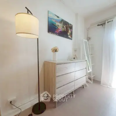 Bright and airy bedroom corner with modern dresser and floor lamp