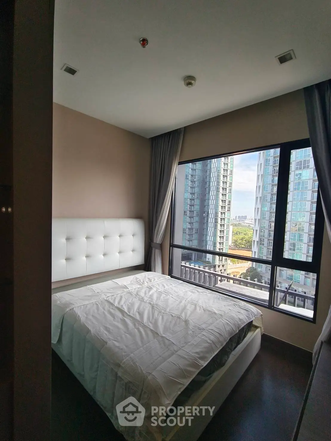 Modern bedroom with large window offering stunning city view in high-rise apartment