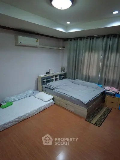 Cozy bedroom with wooden flooring, modern bed, and air conditioning.