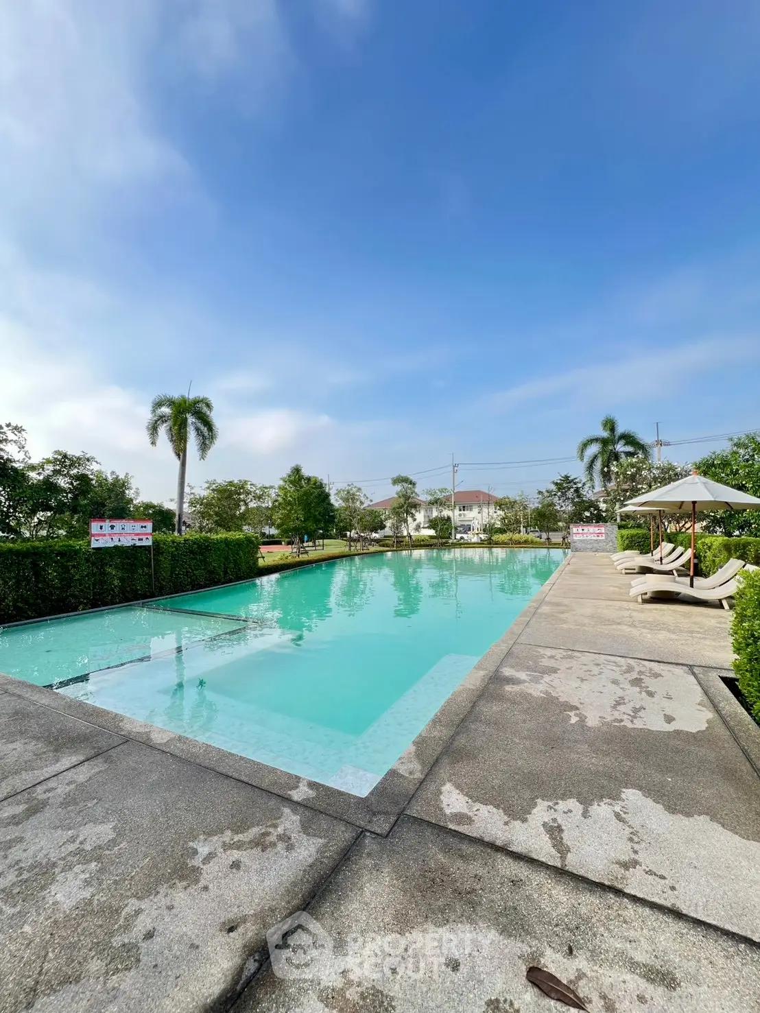 Luxurious outdoor pool area with sun loungers and lush greenery, perfect for relaxation and leisure.